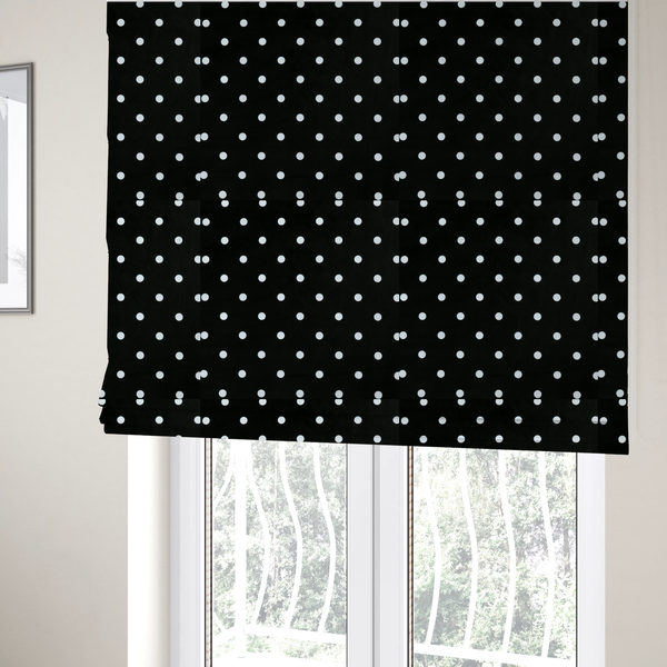 The fabric used to create these Roman blinds is a black fabric pattern featuring evenly spaced white polka dots arranged in horizontal and vertical rows.