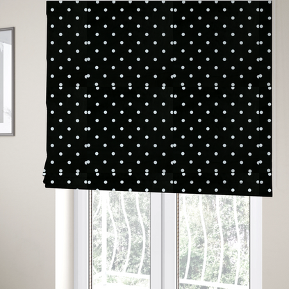 The fabric used to create these Roman blinds is a black fabric pattern featuring evenly spaced white polka dots arranged in horizontal and vertical rows.