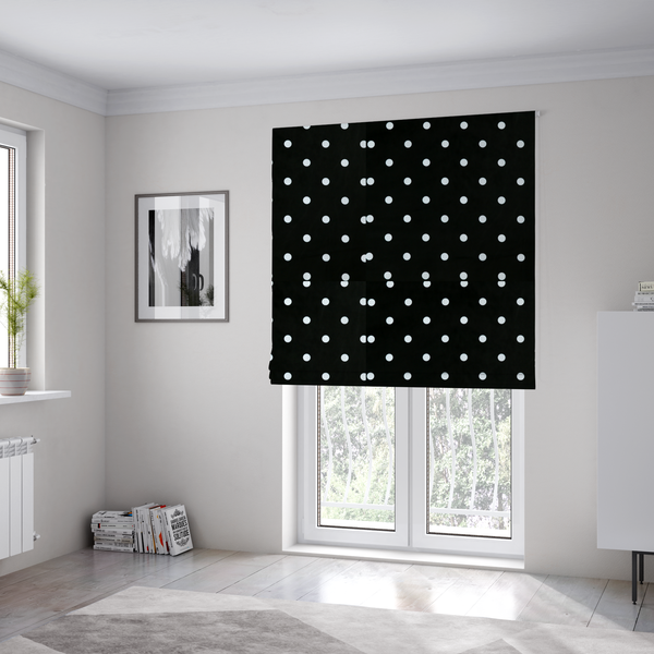 The fabric used to create these Roman blinds is a black fabric pattern featuring evenly spaced white polka dots arranged in horizontal and vertical rows.