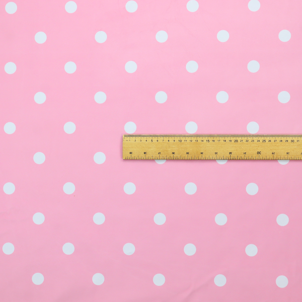 A pink fabric pattern featuring evenly spaced white polka dots arranged in horizontal and vertical rows.
