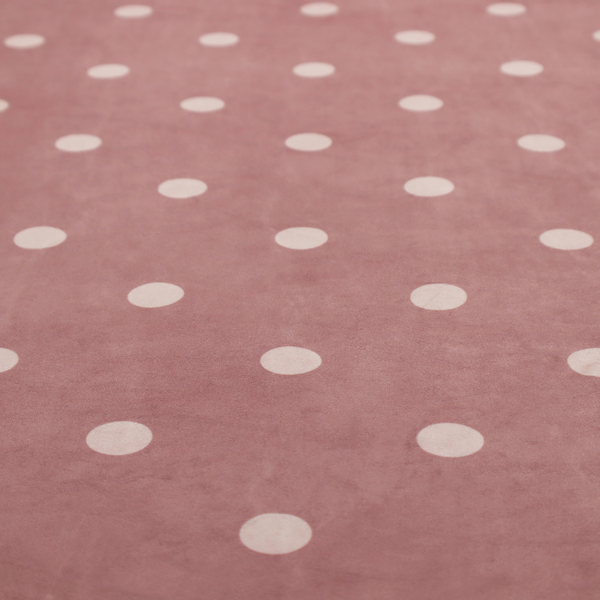 A dusty rose or mauve fabric pattern featuring evenly spaced off-white polka dots arranged in horizontal and vertical rows.