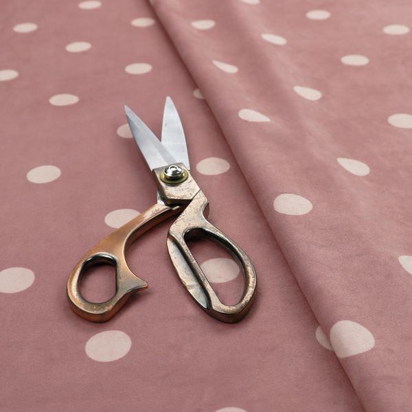 A dusty rose or mauve fabric pattern featuring evenly spaced off-white polka dots arranged in horizontal and vertical rows.