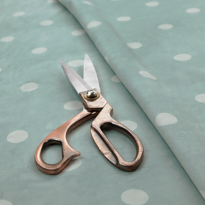 A sage green or pale teal fabric pattern featuring evenly spaced white polka dots arranged in horizontal and vertical rows.
