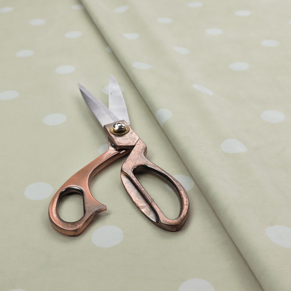 A cream or beige fabric pattern featuring evenly spaced white polka dots arranged in horizontal and vertical rows.