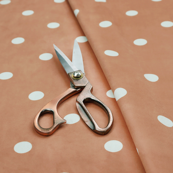 A terracotta or warm brown fabric pattern featuring evenly spaced white polka dots arranged in horizontal and vertical rows.