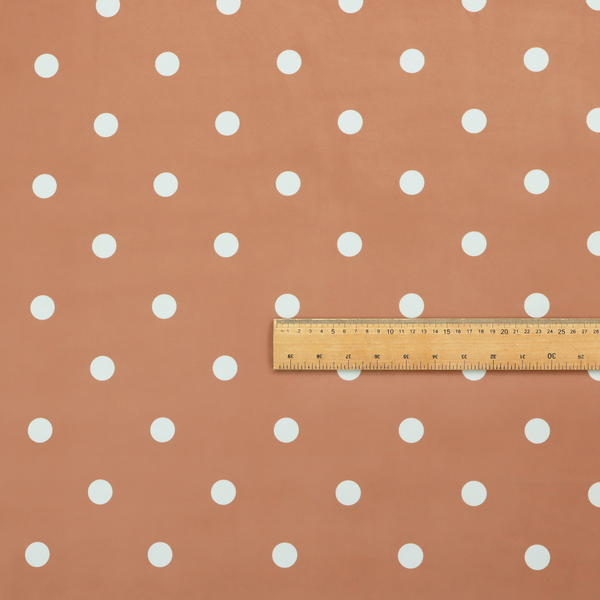 A terracotta or warm brown fabric pattern featuring evenly spaced white polka dots arranged in horizontal and vertical rows.