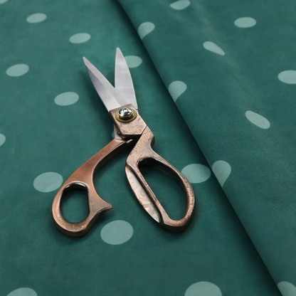 A dark teal or blue-green fabric pattern featuring evenly spaced pale green or off-white polka dots arranged in horizontal and vertical rows.