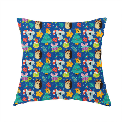 The fabric used to create this handmade cushion is a repeating festive Christmas print on a royal blue background featuring cute cartoon holiday characters, including koalas wearing Santa hats, hedgehogs with antlers, giraffes, Christmas trees, wrapped presents, and stars.   