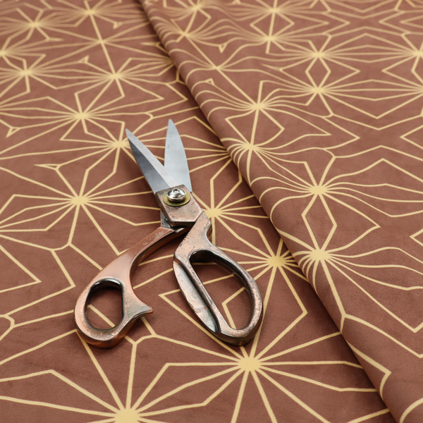 A geometric upholstery fabric featuring an intricate, repeating starburst and lattice pattern in cream lines on a warm terracotta brown background.   