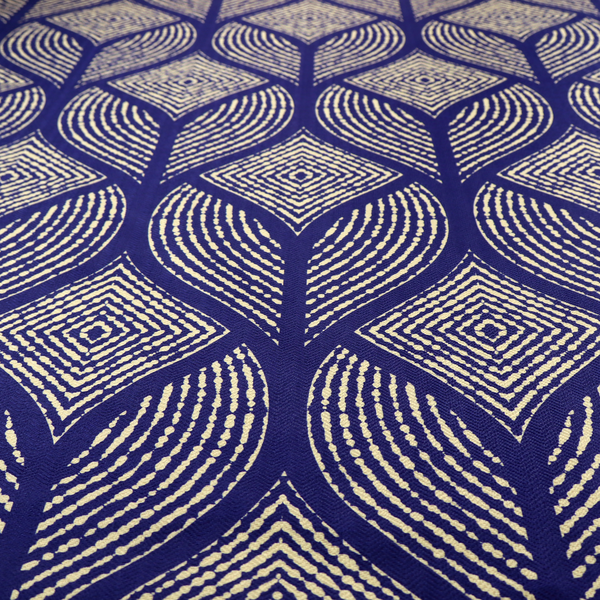 A geometric upholstery fabric featuring an elegant, symmetrical pattern of interlocking diamond shapes and stylized, dotted leaf arches in cream on a royal blue background.   
