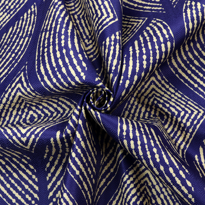 A geometric upholstery fabric featuring an elegant, symmetrical pattern of interlocking diamond shapes and stylized, dotted leaf arches in cream on a royal blue background.   
