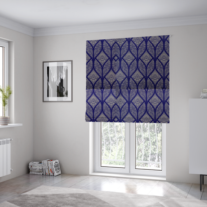 The fabric used to create these Roman blinds is a geometric upholstery fabric featuring an elegant, symmetrical pattern of interlocking diamond shapes and stylized, dotted leaf arches in cream on a royal blue background.   
